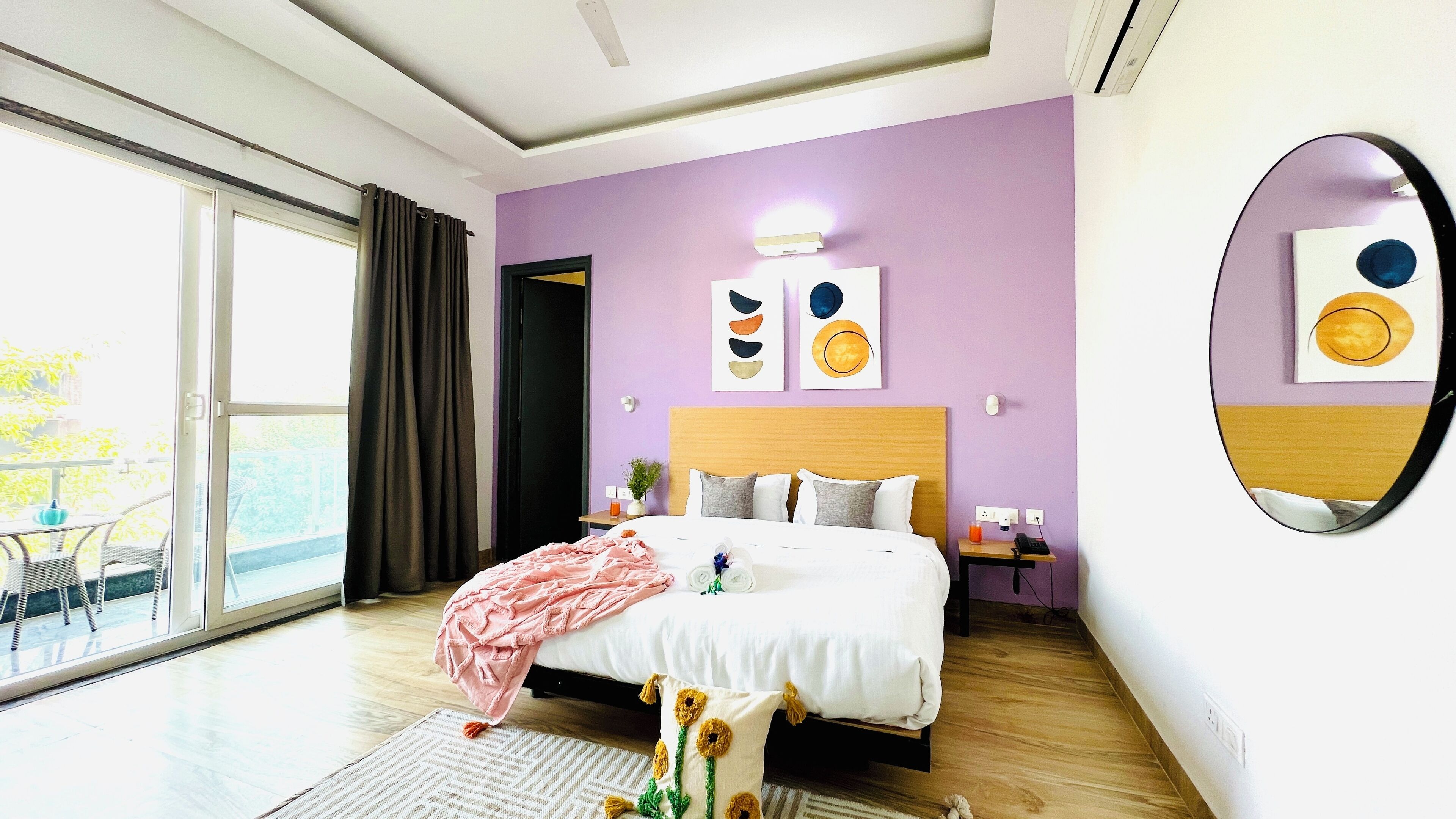 A modern hotel room with a large bed, a balcony, and a view of the outdoors.