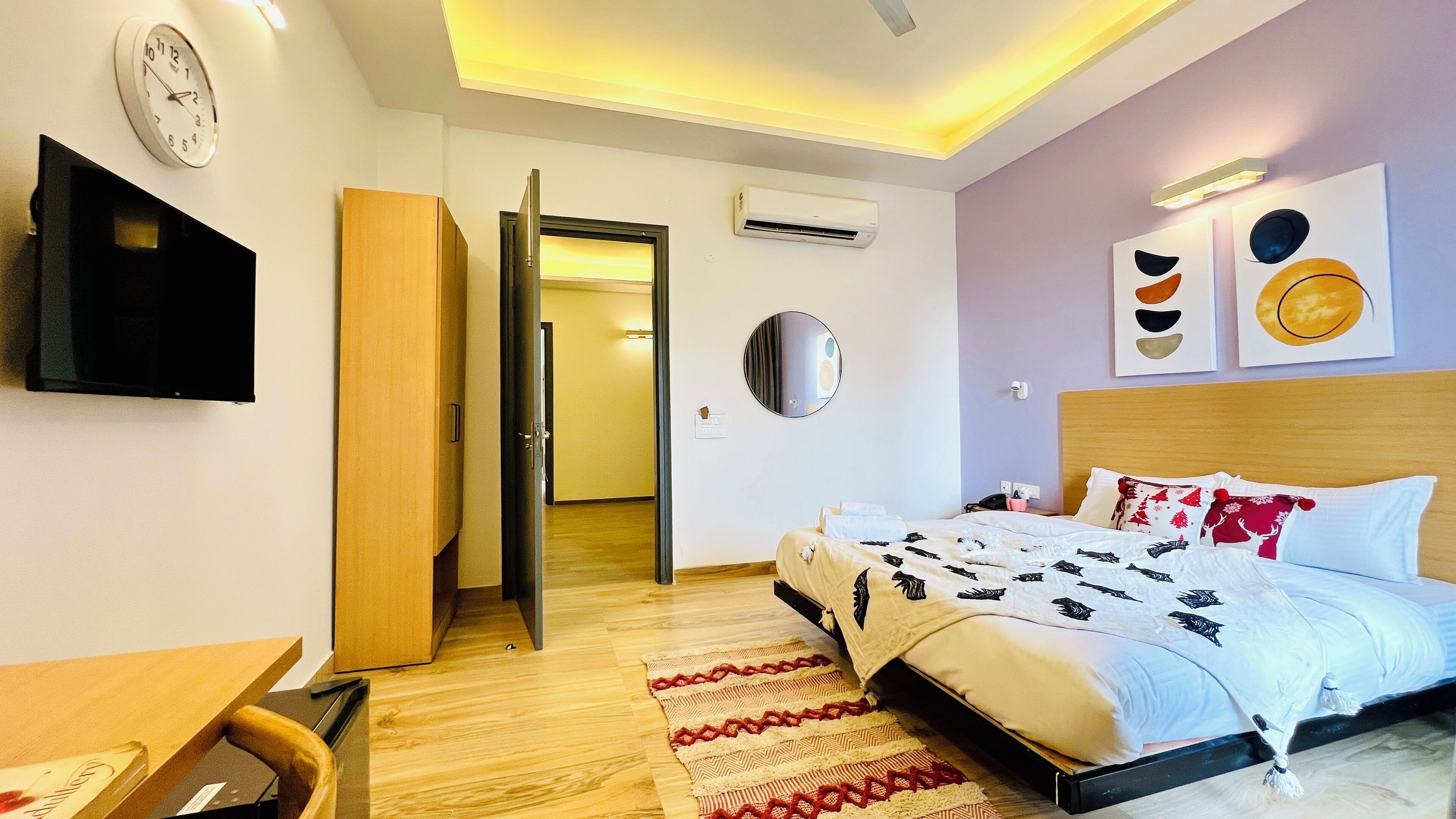 Ein modernes Hotelzimmer mit Bett, Schreibtisch, Fernseher und einer Tür zu einem weiteren Raum.