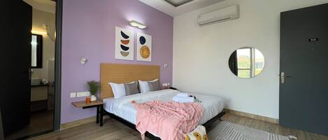 A bedroom with a bed, bedside tables, a mirror, and a door.