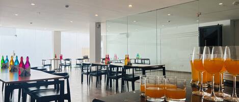 Uma área de jantar moderna com mesas, cadeiras e um balcão de bar.