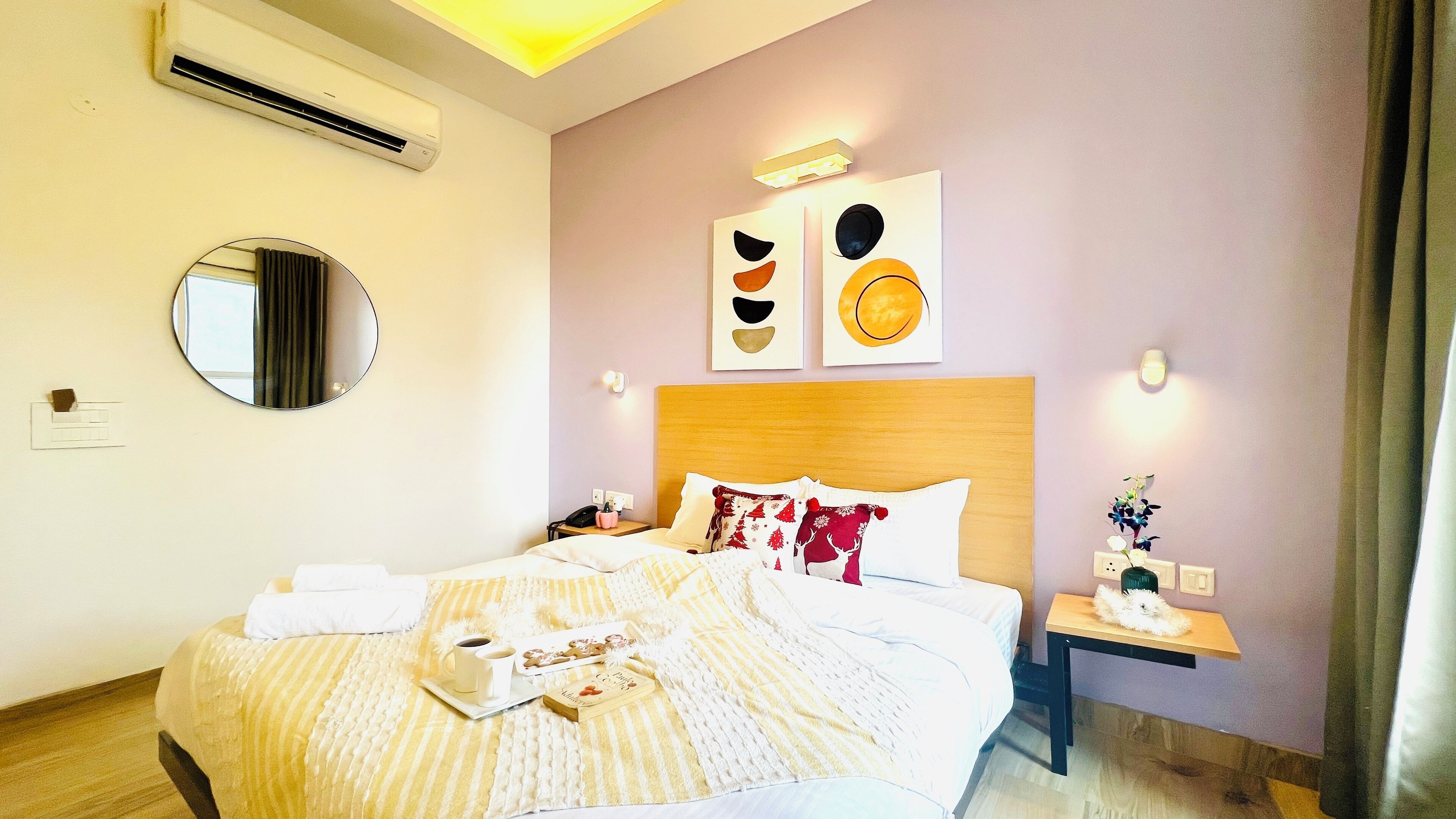 A hotel room with a bed, bedside table, and a mirror.