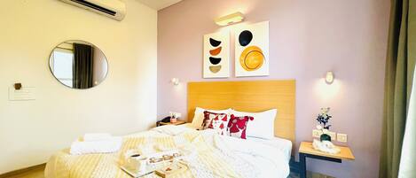 A hotel room with a bed, bedside table, and a mirror.