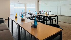 A spacious conference room with multiple tables and chairs, large windows, and a glass partition wall. - ZEN Medicity - Boutique Hotel Gurgaon (Gurugram)