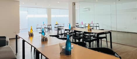 Une salle de conférence spacieuse, dotée de plusieurs tables et chaises, de grandes fenêtres et d’une cloison en verre.