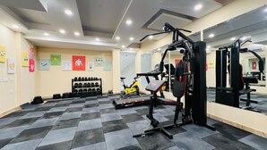 A gym with exercise equipment, dumbbells, and a stationary bike. - ZEN Medicity - Boutique Hotel Gurgaon (Gurugram)