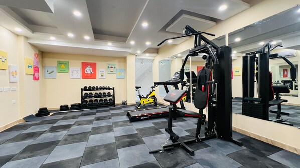 A gym with exercise equipment, dumbbells, and a stationary bike. - ZEN Medicity - Boutique Hotel Gurgaon (Gurugram)