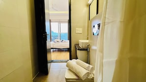 A hotel bathroom with a sink, towel rack, and a view of a balcony with a bed. - ZEN Medicity - Boutique Hotel Gurgaon (Gurugram)