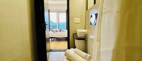 A hotel bathroom with a sink, towel rack, and a view of a balcony with a bed.