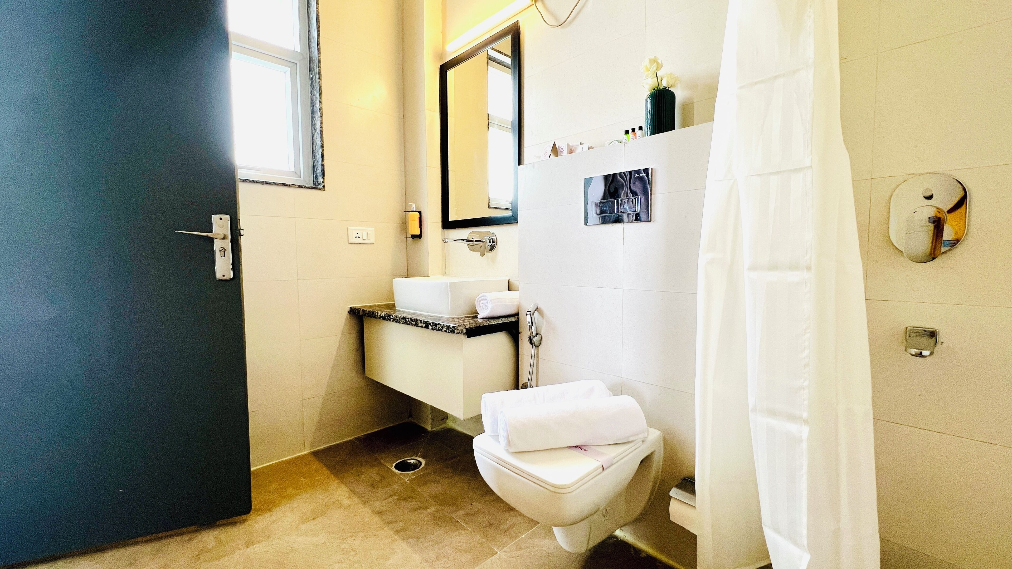 A bathroom with a toilet, sink, mirror, and shower curtain.
