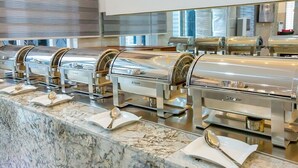 Un buffet proposant une variété de plats en libre-service, un comptoir en marbre et un aménagement intérieur moderne.