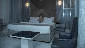 Une chambre d’hôtel moderne, dotée d’un grand lit, d’un bureau et d’un fauteuil en cuir.