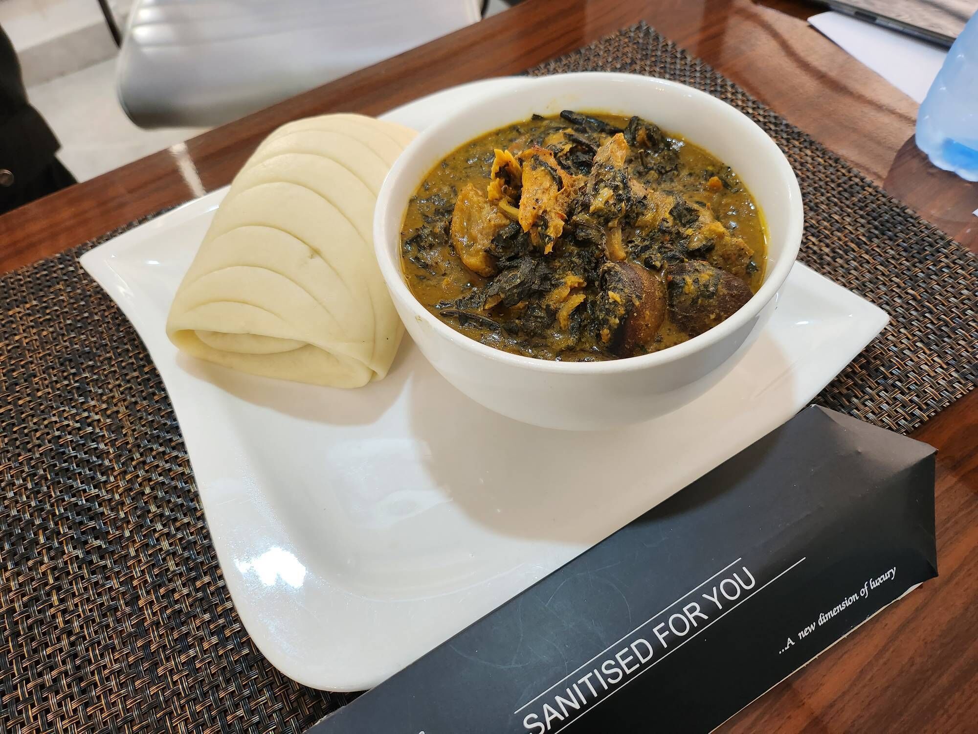 A plate of food with a bowl of stew and a side of sliced bread on a table.