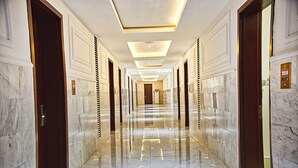 Un long couloir aux murs de marbre poli, avec des portes de chaque côté, un éclairage encastré et une plaque indiquant l’année 2018.
