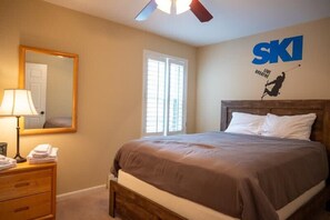 A hotel room with a bed, a dresser, a mirror, and a wall with the logo "SKI LIVE BREATHE". - 3-BR Winterplace Ski-In/Out Okemo Condo w/ Loft (Ludlow)