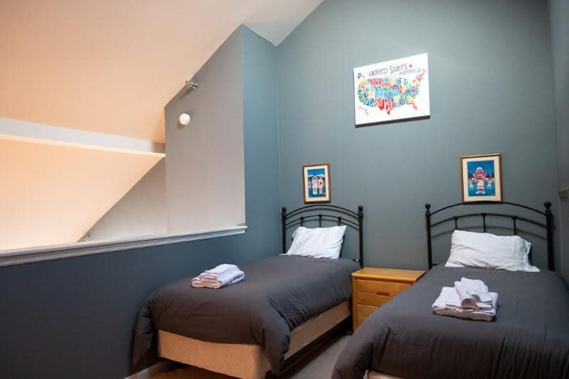 A bedroom with two beds, a window, and a wall-mounted picture.
