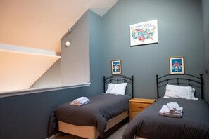 Une chambre avec deux lits, une fenêtre et un tableau accroché au mur.