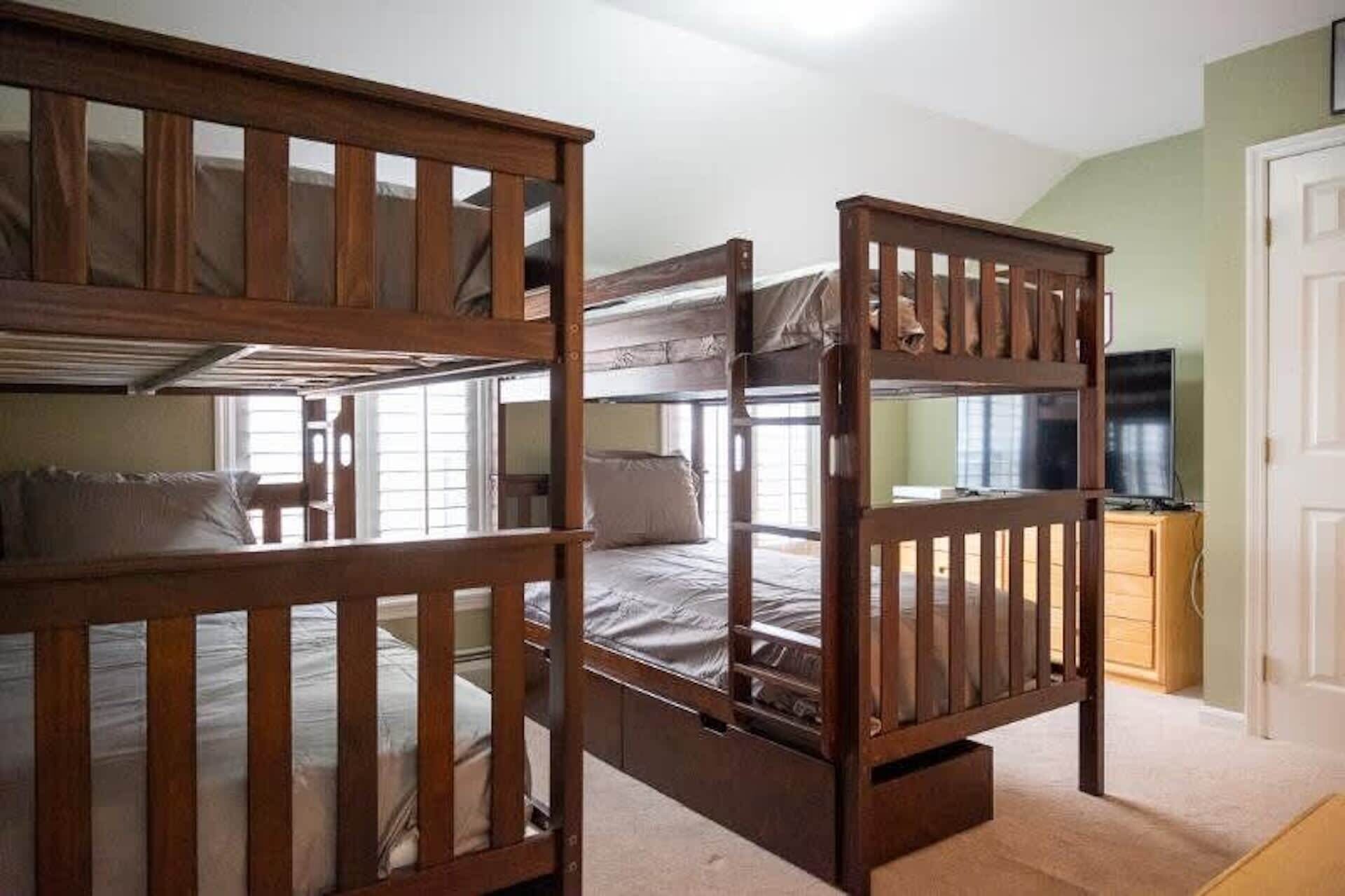 A room with bunk beds, a television, and a door.