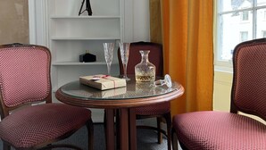 A hotel room with a round glass table, two chairs, a telescope on a shelf, and a window with curtains. - St Cuthbert St Royal Suites (Kirkcudbright)