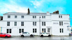 A white building with "ROYAL HOTEL" signage, featuring multiple windows and a prominent chimney. - St Cuthbert St Royal Suites (Kirkcudbright)
