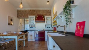 A kitchen with a herringbone floor pattern, a red stove, white cabinets, and a hanging plant.