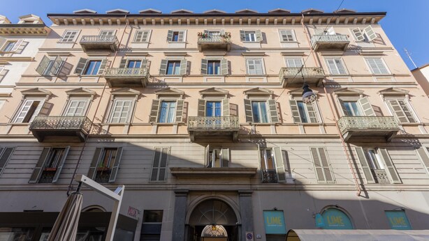 A multi-story building with balconies, a central entrance, and signage for a restaurant.