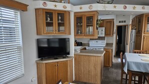 A compact kitchen with wooden cabinets, a built-in microwave, and a central island.