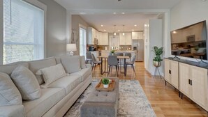 A modern living room with a sofa, coffee table, and a dining area with chairs and a table.