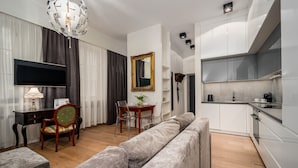 A modern living room with a sofa, a dining table with chairs, a TV, and a kitchen area with cabinets and a countertop. - Apartamenty Sun & Snow Przy Barbakanie (Warsaw)