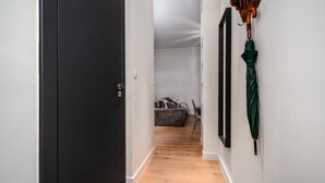 A hallway with a black door, a bed with a headboard, and a green umbrella hanging on the wall. - Apartamenty Sun & Snow Przy Barbakanie (Warsaw)