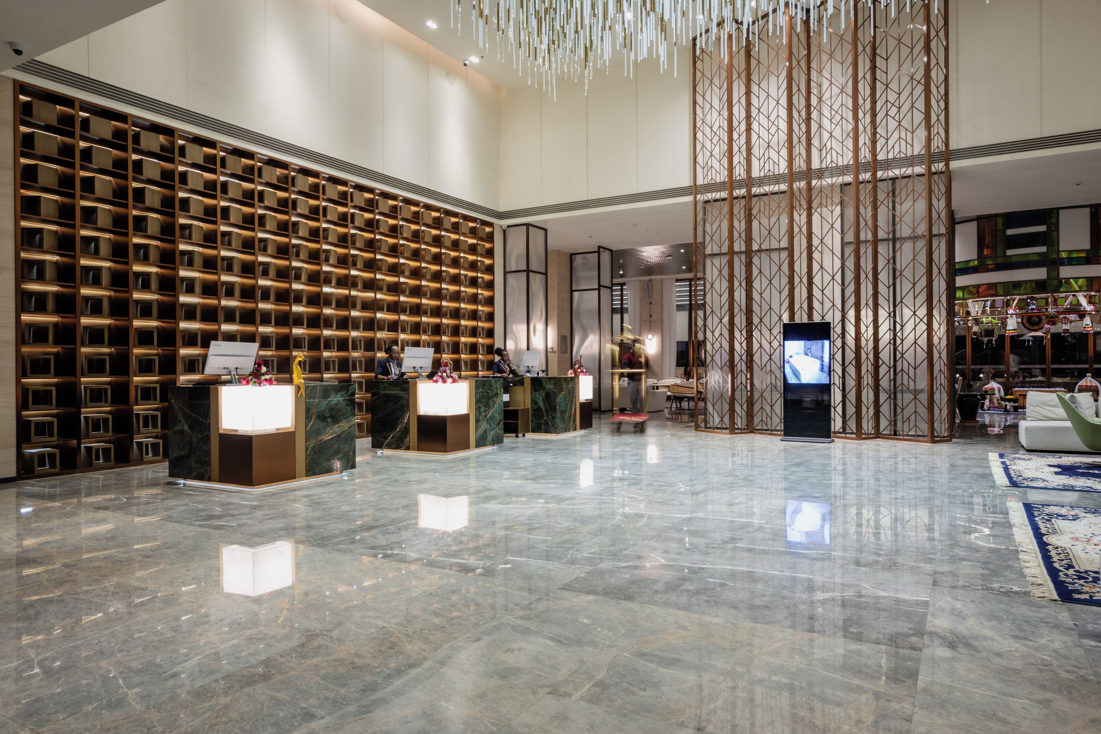 A spacious lobby with a marble floor, a reception desk, a wall of bookshelves, and a decorative screen.