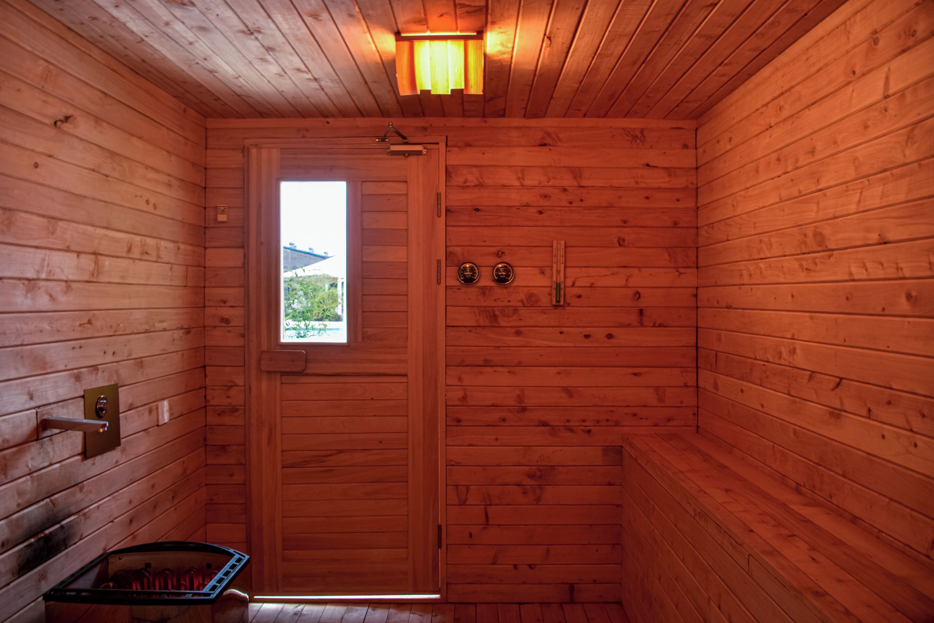 A wooden cabin with a single door, a small window, and a built-in bench.