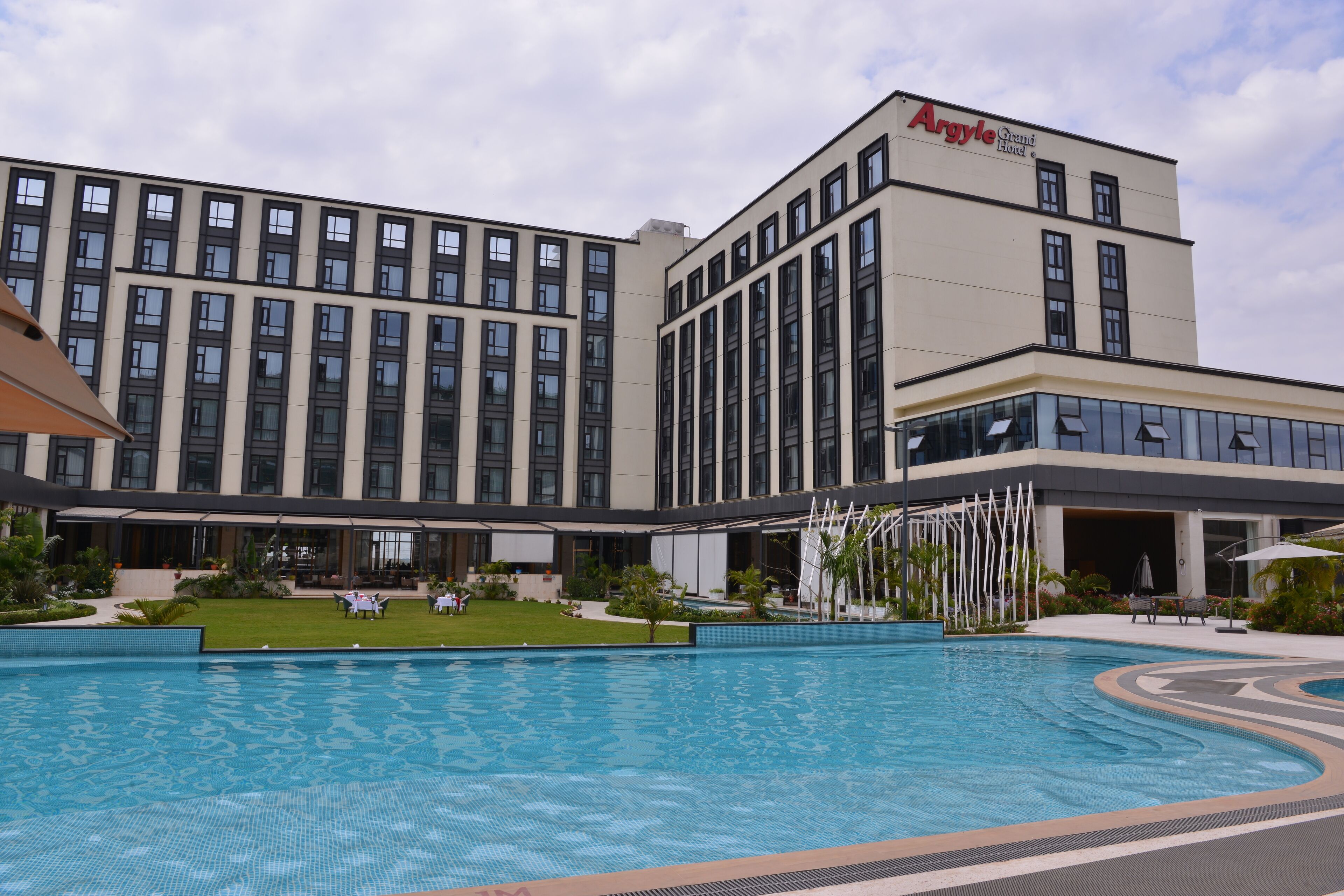 Un hotel con piscina, zona de estar exterior y fachada de edificio moderna.