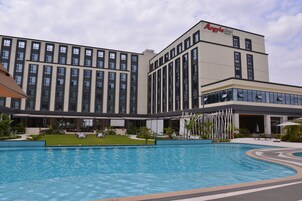 Un hotel con piscina, zona de estar exterior y fachada de edificio moderna.