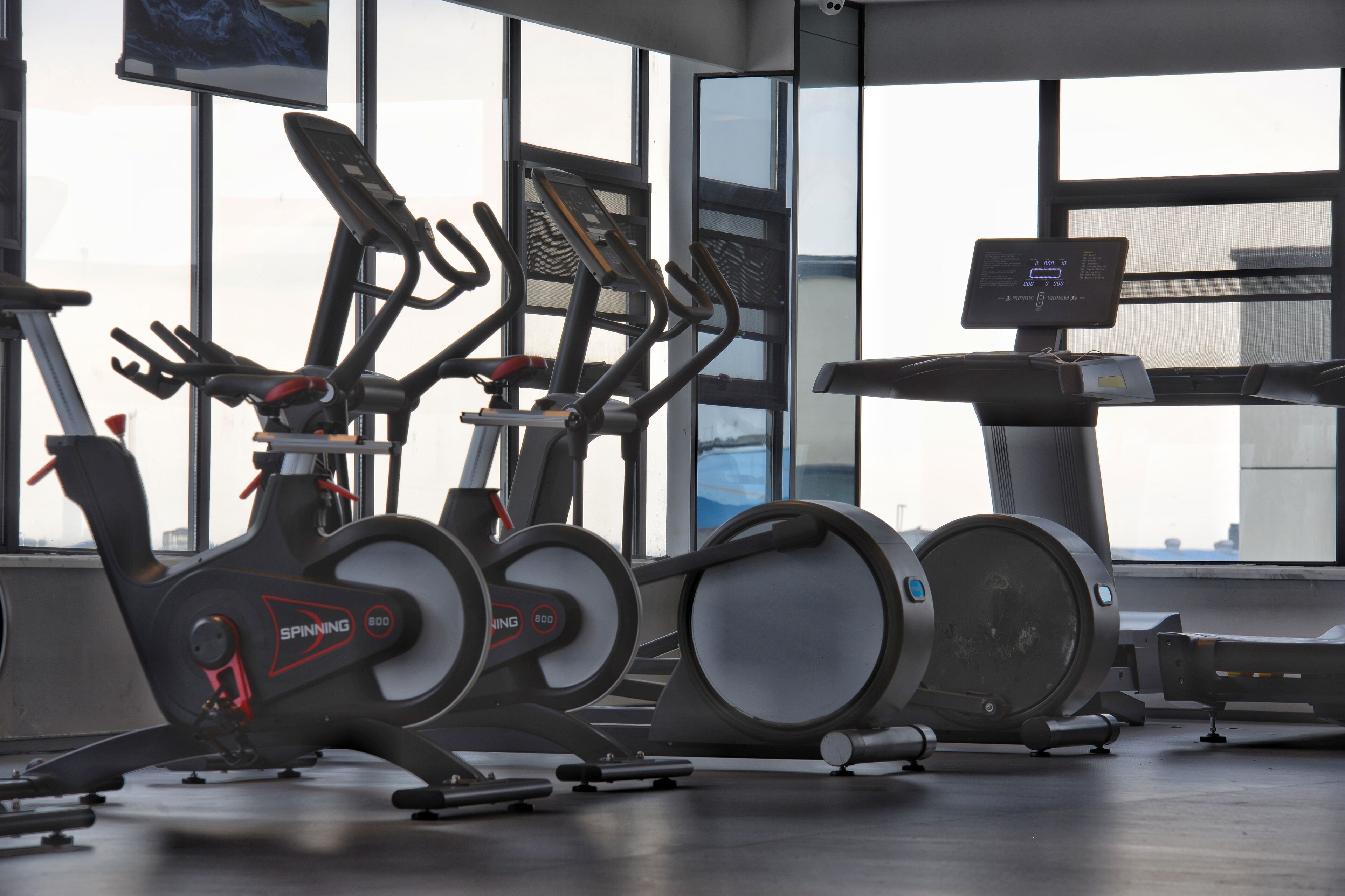 Une salle de sport équipée de vélos d’appartement, d’un tapis de course et d’un rameur.