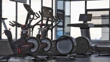 Une salle de sport équipée de vélos d’appartement, d’un tapis de course et d’un rameur.