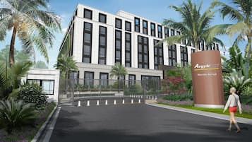 Un hotel moderno con una entrada destacada, rodeado de exuberante vegetación y palmeras.