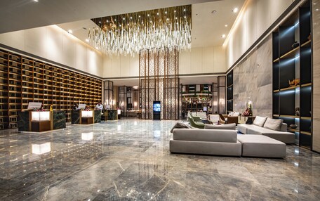 A spacious lobby with a marble floor, a large sectional sofa, and a decorative hanging light fixture.