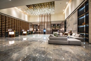 Un vestíbulo amplio con piso de mármol, un sofá modular grande y un elegante aplique colgante.
