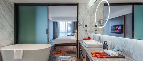 A modern bathroom with a large bathtub, a double sink, and a large mirror.