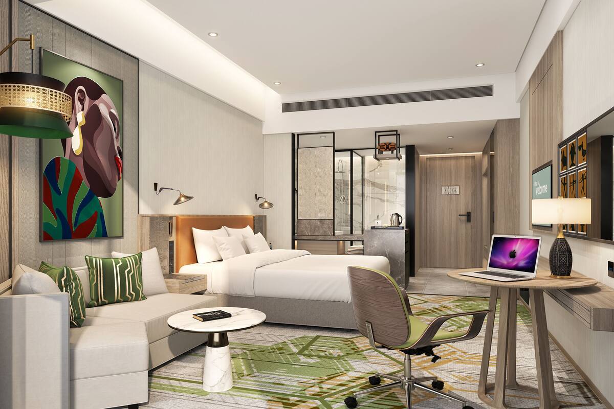 Une chambre d’hôtel moderne équipée d’un lit, d’un canapé, d’un bureau avec un ordinateur portable et d’un espace douche.