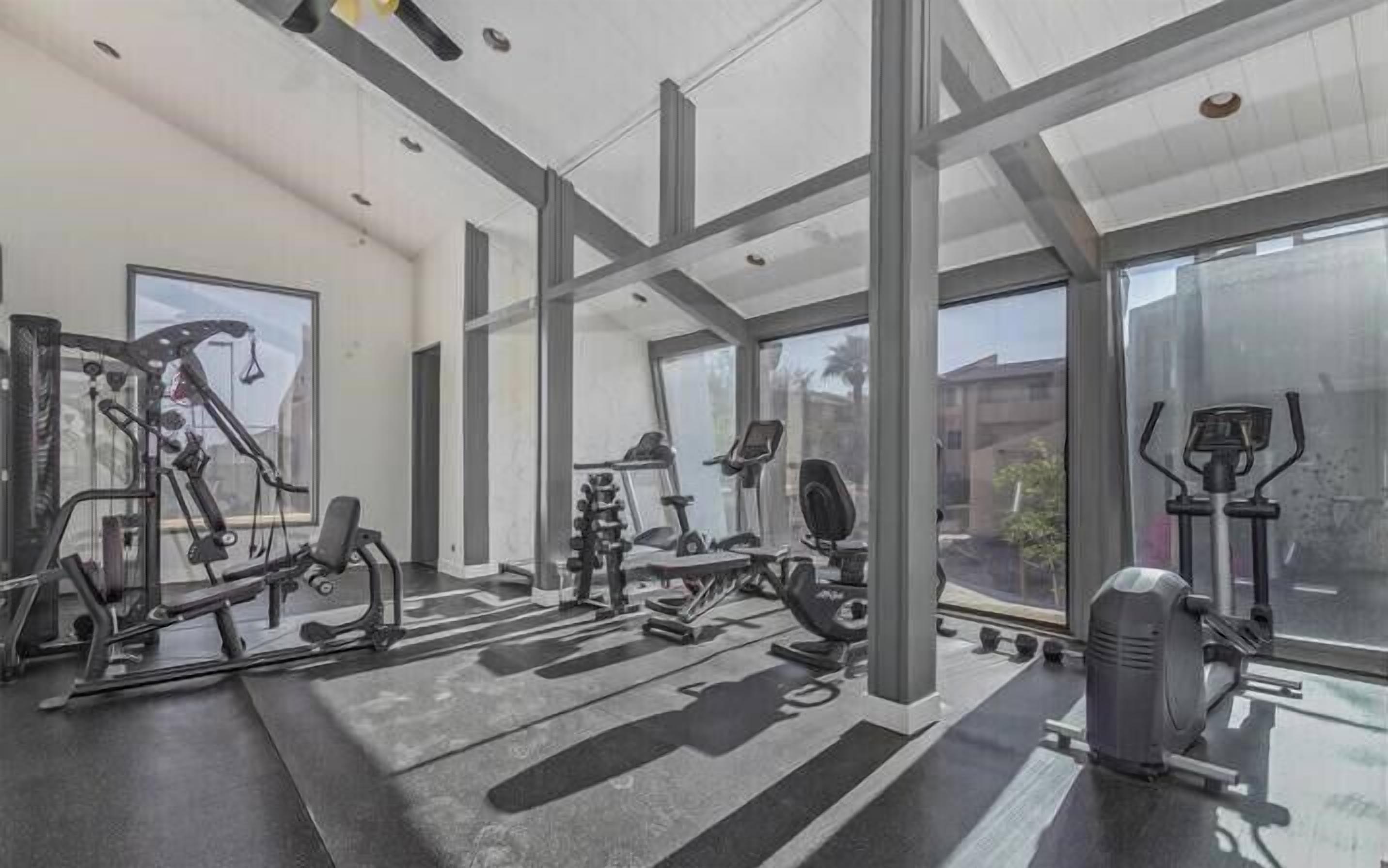 Ein Fitnessstudio mit unterschiedlichen Trainingsgeräten, großen Fenstern und modernem architektonischem Design.