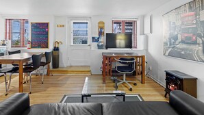 A modern living room with a sofa, a dining table with chairs, a TV, and a fireplace. - Free ferry | Aux Trois Filles (Lévis)