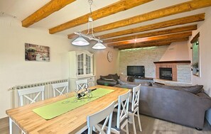A cozy living space with a wooden dining table, white chairs, a grey sofa, and a stone fireplace. - Nice apartment in Visnjan with WiFi (Visnjan)