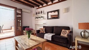 Ein Wohnzimmer mit Couch, Kissen, Kamin und Blick ins Freie.