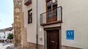 Ein Gebäude mit einer Stein-Fassade, einem Holzbalkon und einem blauen Schild mit der Aufschrift 'AT'.