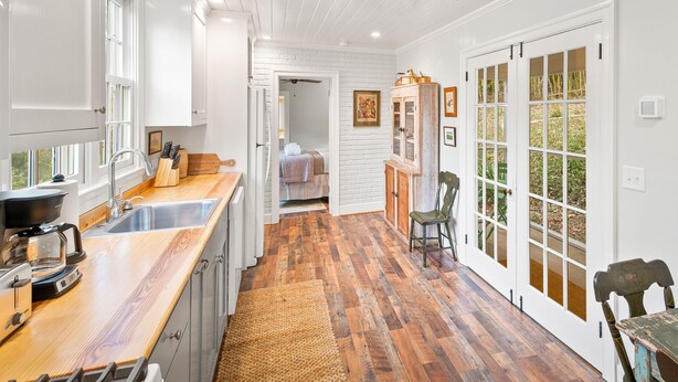 Una cucina con pavimento in legno, mobili bianchi e una macchina per il caffè.