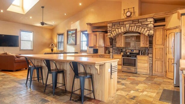 Una cocina amplia con una isla grande, armarios de madera y una chimenea de piedra.