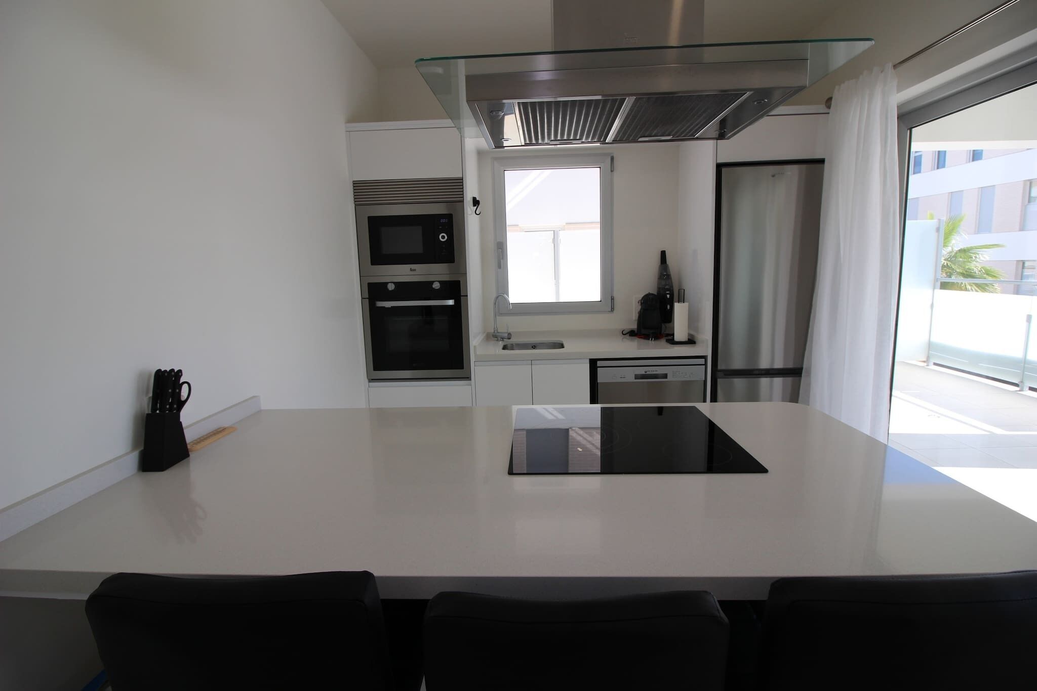 Una cocina moderna con una isla central, horno empotrado, microondas y lavavajillas.