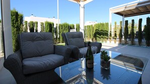 A glass-top table with two chairs, a bottle of wine, and two glasses. - Groundfloor Varudi Aguas Nuevas, Torrevieja (Torrevieja)