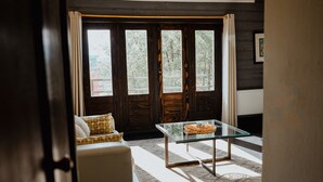 A room with a glass table, a white sofa, and a large window with curtains. - Hotel Newen BnB (Pucón)